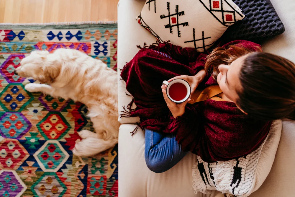 Woman drinking tea next to her dog